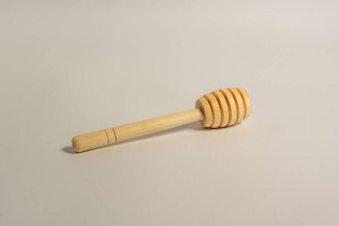 Beyaz arka planda tek tahta ballı çiseleyici, yalıtılmış bal çubuğu, bal için tahta kaşık