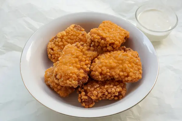 Kızarmış baloncuklu çıtır tavuk nuggetları beyaz tabakta izole edilmiş, beyaz fırın kağıdında..                         