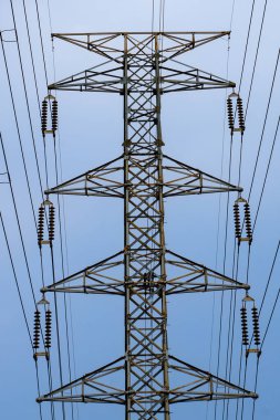 Yüksek voltajlı elektrik direği. Mavi gökyüzünde izole edilmiş mesafeye uzanan sayısız kablo var..