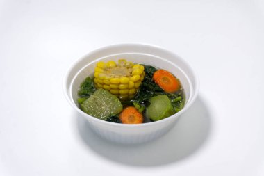 Sayur Bening Bayam, Spinach Clear Vegetable. Indonesian food of spinach, spinach soup with carrots, chayote and corn. Served in white bowl isolated on white background clipart