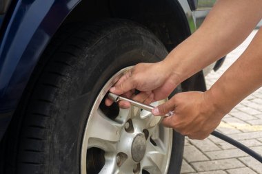 Bir adamın elleri kompresörle arabanın tekerleğine hava pompalıyor. Hava basıncını kontrol ediyorum. Otomobil tekerleğine hava pompalıyorum. araç güvenli konsept.