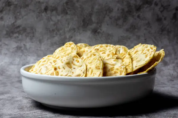 Keripik tempo veya tempeh cipsleri soya fasulyesinden yapılır ve beyaz tabakta servis edilir.