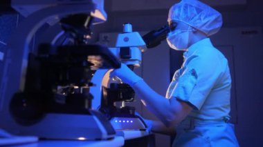 Tıp Bilimi Laboratuvarında: Güzel mikrobiyolog Mikroskop Altında Analiz Örnekleri Bakıyor. Yüksek teknolojili ekipmanlarla çalışan zeki bir bilim adamı.. 