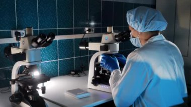 Tıbbi Bilimler Laboratuvarı 'nda mikrobiyolog Mikroskop Altında Analiz Örnekleri Bakıyor. Yüksek teknolojili ekipmanlarla çalışan zeki bir bilim adamı.. 