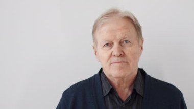 Yetişkin bir adamın kapalı mekanda kameraya bakarak poz vermesi. Beyaz arka planda kameraya bakan bir adamın portresi..