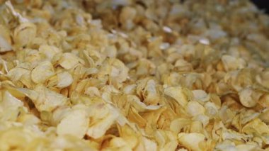 Kızarmış patates cipsi fabrikadaki endüstriyel taşıma bandına konuyor. Kızarmış cips yığını fabrikadaki bir konteynırda son buluyor. Chips Fabrikası.