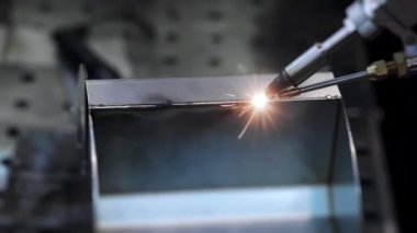 Fabrika işçisi metali kaynaklıyor. Adam kaynak yapıyor. Kaynak makinesi kullanarak argon veya elektrot ile kaynak yapmak. Metal yapılar üreten bir endüstriyel girişim. Kıvılcımlar ve parıltılar uçuşuyor. 