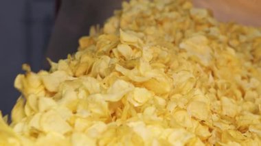 Kızarmış patates cipsi fabrikadaki endüstriyel taşıma bandına konuyor. Kızarmış cips yığını fabrikadaki bir konteynırda son buluyor. Chips Fabrikası.
