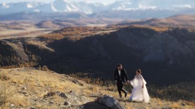 Yeni evliler. Dağlarda evli bir çift. Gelinlik giymiş bir adam ve bir kadın kar kaplı dağların arka planına karşı. Düğün çifti. Mutlu bir aile.. 