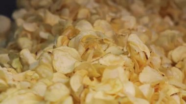 Kızarmış patates cipsi fabrikadaki endüstriyel taşıma bandına konuyor. Kızarmış cips yığını fabrikadaki bir konteynırda son buluyor. Chips Fabrikası.