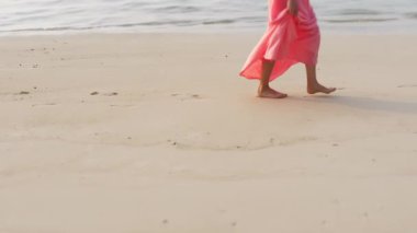 İnce kadın bacakları ve ayakları kumlu sahilde deniz suyu dalgaları boyunca yürüyor. Güzel bir kadın deniz kıyısında sörf yapıyor. Okyanusta yıkandıktan sonra kıyıya çıkan kızlar..