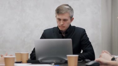 Ofisteki iş toplantısında erkek takım lideri yöneticilerle konuşuyor, dizüstü bilgisayarla ilgili bilgileri kontrol ediyor, strateji planlıyor. Bütünlük projesi kavramı.