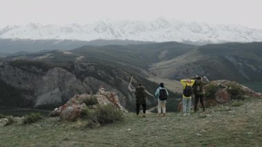 Seyahat başarısı olan bir grup yürüyüşçü ve beraberce manzara manzarası yüksek dağın tepesinde kollarını kaldırıyor. Turizm ve zirve motivasyonunda başarılar..