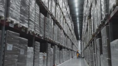 Depo için depo. Mühendis raflardan paletleri kaldırmak için bir forklift kullanıyor.. 