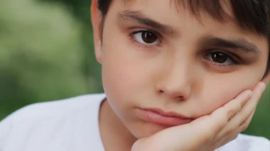 Üzgün bir çocuğun yakın plan portresi. Sokaktaki üzgün çocuk. Kameraya bakan üzgün bir çocuğun portresi. Küçük, güzel bir çocuğun yüzü. Üzgün küçük çocuk..