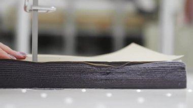 Giysi üretim fabrikası. Bir tekstil fabrikası işçisi otomatik kesim makinesiyle birkaç kat kumaş kesiyor..