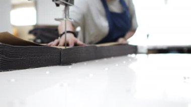 Giysi üretim fabrikası. Bir tekstil fabrikası işçisi otomatik kesim makinesiyle birkaç kat kumaş kesiyor..