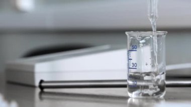 Ölçüm kabına yakın çekim. Sıvı bir ölçü kabına dökülüyor. Ekoloji laboratuvarı. Bilimsel Laboratuvar.