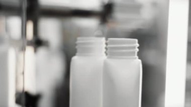 Kozmetik üretim tesisi. Beyaz şişeler doldurulmak üzere konveyör boyunca hareket eder. Şampuan, duş jeli ve sıvı sabun üretimi. Ürün montajı için makine. 