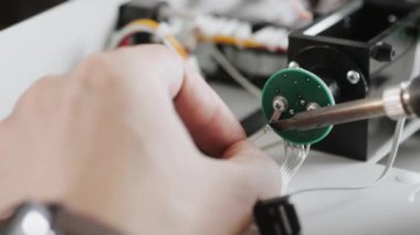 Mühendis ya da teknisyen, tahtadaki bir çiviye teller yerleştirir. Lehim demiri yakın plan. Teknik becerileri ve elektronik bakımını göster.