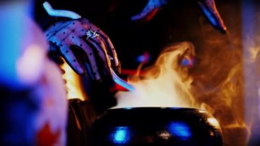 Bir büyücünün, içinden beyaz duman çıkan bir saksı iksiri uzatması. Cadı bir büyü yapıyor. Mistik Cadılar Bayramı Kutlaması.