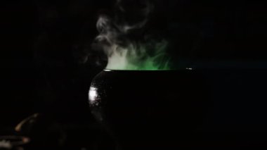 Esrarengiz bir iksir ve siyah bir çanaktan çıkan yeşil dumanlı kara büyü kazanı. Cadılar Bayramı ve büyücülük konsepti.