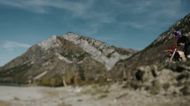 Enduro yarışçısı bir uçurumdan güzel dağların arka planına doğru motosikletle atlıyor. Bir yarışçı motosiklete atlar. Dağlarda uçuk bisiklet sürmek.