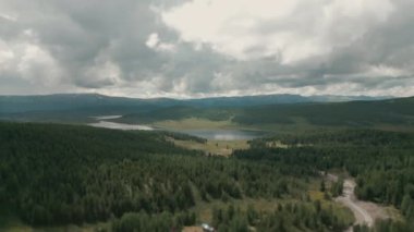 İnsansız hava aracı bir dağ gölünün üzerinde uçuyor. Dağların arka planına karşı bir dağ gölü manzarası. Göldeki bulutların yansıması.