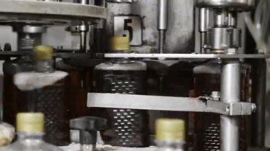 Fabrikadaki içkileri şişelemek için bir teknoloji hattı. Plastik şişe kapaklarının otomatik vidalarını yakın çekim. İçecek üretimi.
