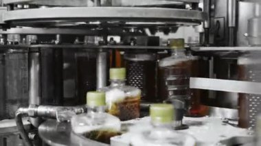 Fabrikadaki içkileri şişelemek için bir teknoloji hattı. Plastik şişe kapaklarının otomatik vidalarını yakın çekim. İçecek üretimi.