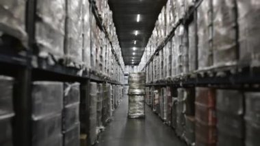 Bitmiş ürünler ve hammaddelerden oluşan modern bir depoda forklift operasyonu. Bir depo çalışanı depoya forklift sürüyor. Modern bir depoda forkliftler..
