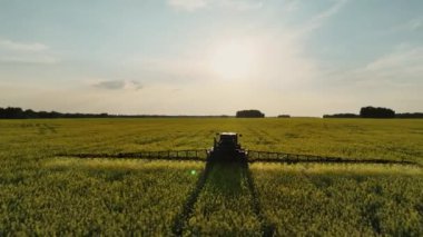 Bir tarlaya gübre püskürten bir traktörün hava görüntüsü. İyi bir hasat için tarlayı gübrelerle işliyor. Tarımsal makineler sahada.