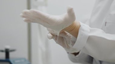 Beyaz önlüklü bir doktor ya da laboratuvar çalışanı beyaz koruyucu eldivenler giyer. Tıbbi hazırlıkta güvenlik ve hijyen.