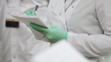 Tıbbi eldivenli bir doktor not defterine not alır. Bir fen laboratuarı öğrencisi not defterine bir ders yazar. Tıp fakültesinde okuyorum..