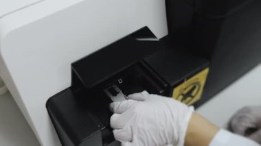 Laboratuvarda çalışan DNA sıralayıcısı. Eldivenli bir araştırmacı DNA örneklerini sıralayıcıya yerleştirir. Yüksek teknoloji laboratuvar ekipmanları..