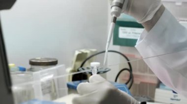 Bir genetik laboratuvarı araştırmacısı bir pipetle numune bırakıyor. Modern bir laboratuvarda DNA üzerinde çalışma kavramı. Bilim ve tıp. Genetik Çalışmalar İçin Laboratuar Deneyleri.
