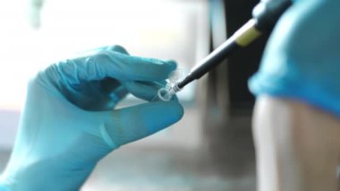 Eldivenli bir bilim adamının, otomatik bir pipetle epindorf 'a örnek damlatırken yakın çekimi. Araştırma ve Bilim.