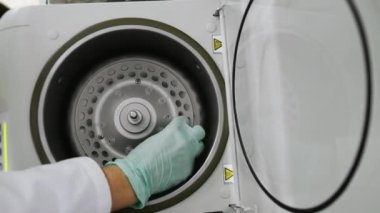 Beyaz eldivenli bir laboratuvar asistanı Eppindorf 'u laboratuvar santrifüjüne koydu. Ve reaksiyonları karıştırıyor. Modern bilim laboratuvarı.