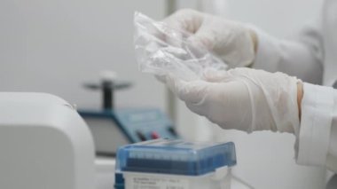Laboratuvar teknisyenlerinin yakın çekimleri beyaz eldivenleriyle bir paketten otomatik pipo için ipuçları alıyorlar. Modern bilim laboratuarı. Bilim ve tıp. 