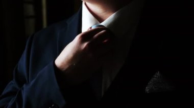 Kravatını düzelten takım elbiseli bir erkek işadamının yakın çekimi. Zarif giyimli bir adam kravatını düzeltir. Damat kravatını düzeltir..