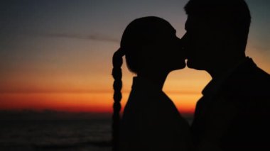 Günbatımı geçmişine karşı evli bir çiftin siluetleri. Bir erkek ve bir kadın gün batımına karşı öpüşürler. Düğün çifti. Mutlu aile.