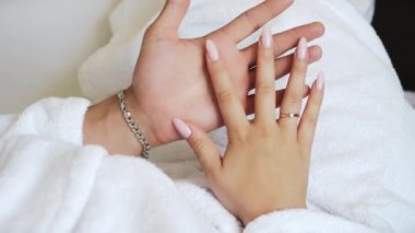 Sevgi dolu bir çiftin ellerine yakın çekim. Beyaz önlüklü bir adam ve bir kadın yatağa uzanıp birbirlerini okşarlar..