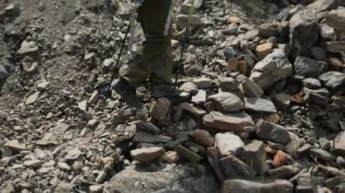 Sırt çantalı ve yürüyüş direkli bir turist kayalara tırmanıyor. Turist bacaklarına yakın çekim. Dağ turizmi. Dağlarda turistler.