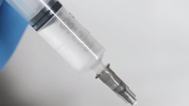 Aşıyla birlikte şırıngaya yakın çekim. Bir araştırmacı bir maddeye şırınga enjekte eder. Doktor hastaya bir iğne yapar..