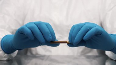 Mavi eldivenli eller sigarayı iki parçaya ayırıyor. Sigara içmek sağlığa zararlıdır..