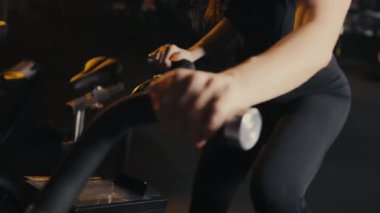 Spor salonunda egzersiz bisikletinde egzersiz yapan bir kızın ellerinin yakın çekimi. Egzersiz bisikletinde kardiyo çalışması. Kız spora gidiyor.. 