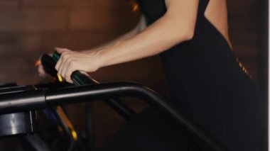 Egzersiz makinesinin elini tutan bir sporcunun ellerine yakın çekim. Spor üvey antrenörü. Bir kız spor salonunda antrenman yapıyor..