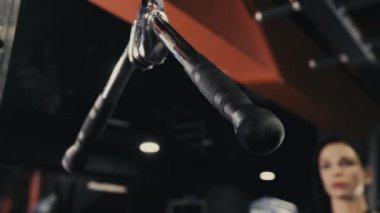 Egzersiz makinesinin kulplarını tutan bir bayan sporcunun ellerine yakın çekim. Bir bayan sporcu spor salonunda antrenman yapıyor..