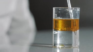 Bir kimyager, motor yağı ya da yakıtı test tüpüne kalite analizi için ayırıcı ile karıştırıyor. Kimya laboratuvarı. Yakıt veya motor yağının kalitesi kontrol ediliyor.