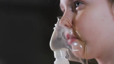 Nefes alan tıbbi maske takan küçük bir kız. Kız solunum yapıyor. Solunum hastalıklarının tedavisi için. Nefes alan tıbbi maske takan küçük bir kız.. 